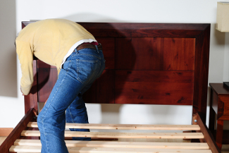 Unrecognizable person assembling a new bed in a room.