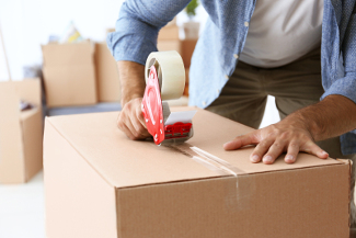 House moving concept. Closeup of man packing cardboard box