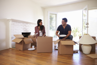 Couple Unpacking Boxes In New Home On Moving Day